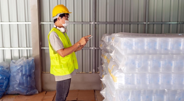 worker checking the stock of plastic bottles in the warehouse and comparing the balancing number