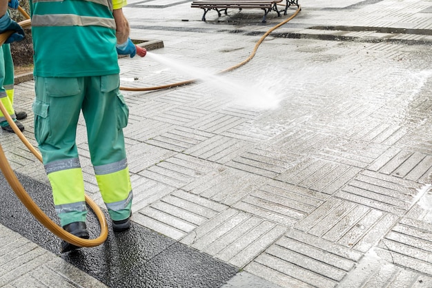 Worker cleaning a city square with water using a hosepipe Public maintenance concept Copy space