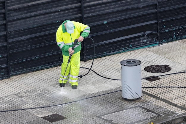 Worker cleaning a sidewalk with high pressure water jet machine