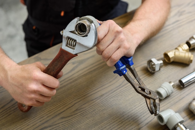 Worker connecting elements of the plumbing with the adjustable wrenches