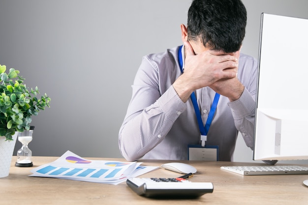 Worker covered his face while sitting at his desk .