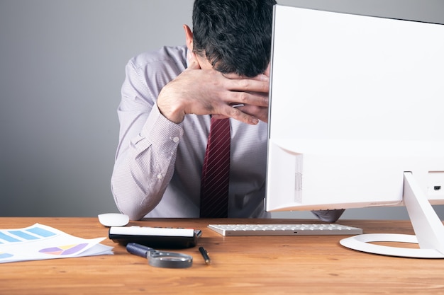 Worker covered his face while sitting at his desk .