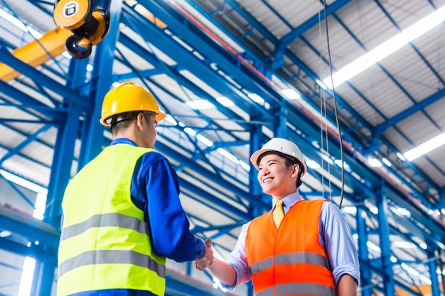 Worker and customer having agreement in factory shaking hands