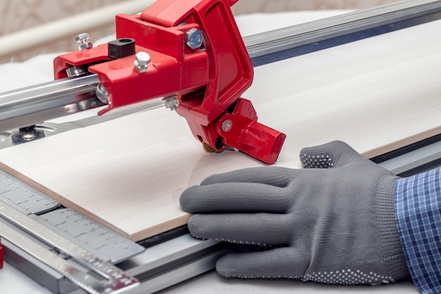 A worker cuts facing tiles with a tile cutter