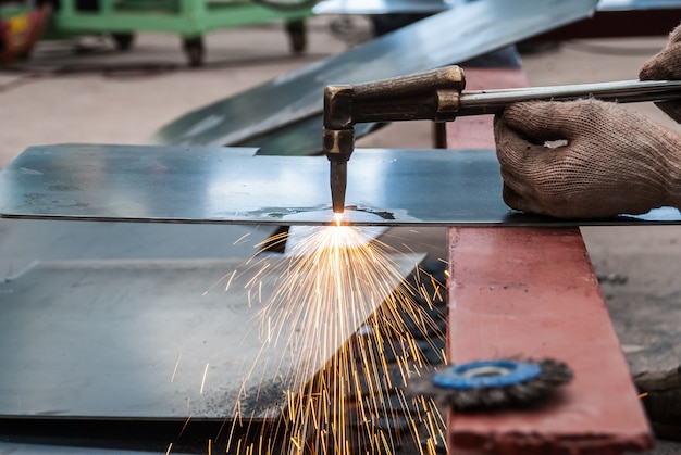 worker cutting steel sheet using metal torch in factory