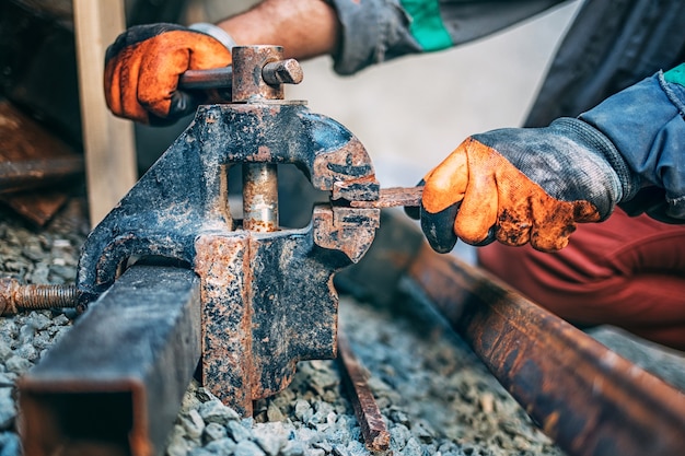 Worker fixes a metal part in a vise before cutting, Close-up