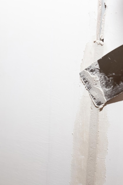 Worker fixing cracks on ceiling spreading plaster using trowelplastering cement on wall