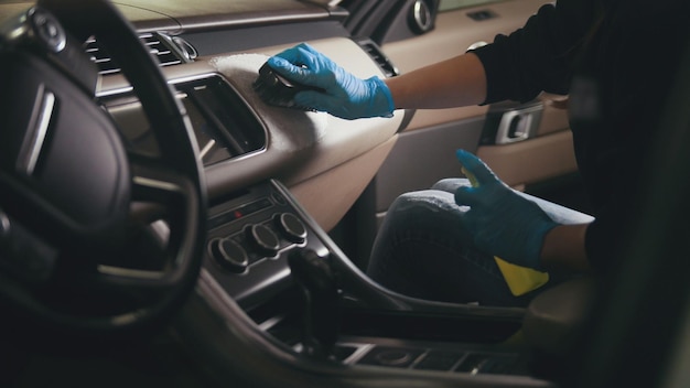 Worker in gloves is washing with brush a car interior and seats, close up