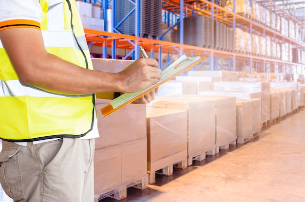 Worker hand holding clipboard inventory cargo management in storage warehouse