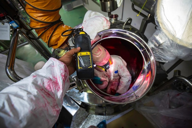 Worker hand holding gas detector inspection safety gas testing at front manhole stainless tank to inside confined