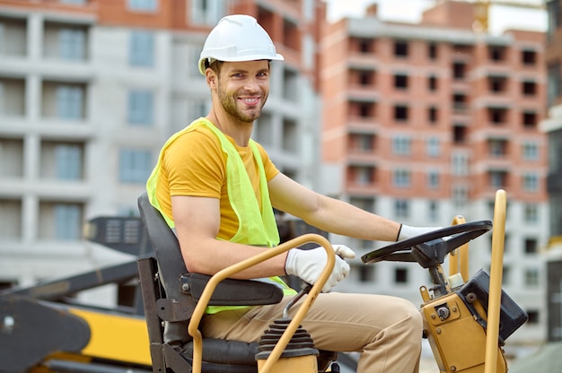 Worker in a hardhat at the steering wheel of a vehicle