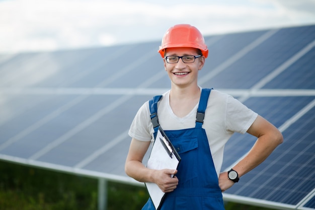 Worker in helmet standing, solar panels behind him.