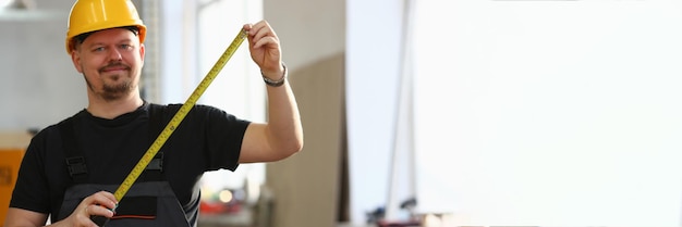 Worker in helmet and uniform holds tape measure