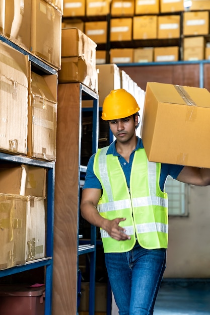 The worker holding a box in the warehouse