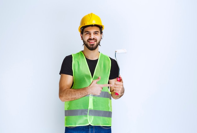 Worker holding a white trim roller for wall painting .