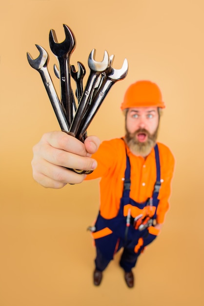 Worker holds wrenches wrenches repairment tools building industry technology spanner bearded builder