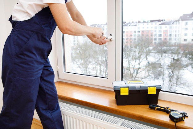 The worker installing and checking window in the house