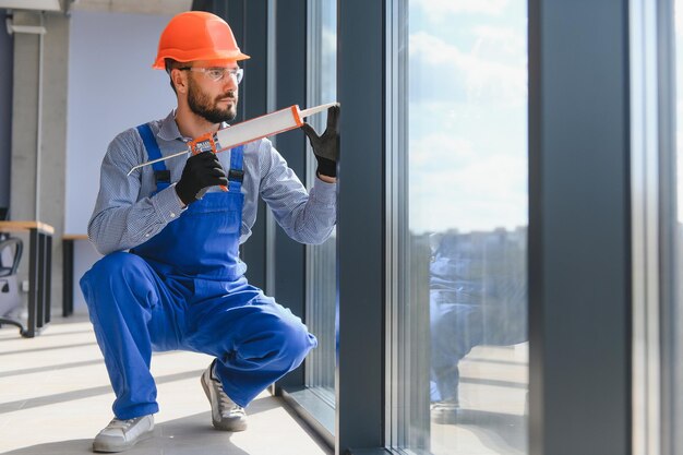 Worker installing plastic window indoors