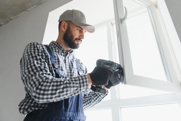 Photo worker in installing white plastic upvc window on house