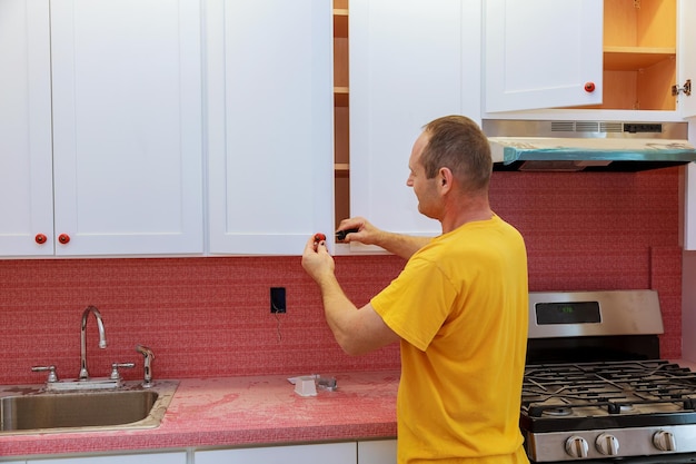 Worker installs doors to kitchen cabinet installation of doors on kitchen cabinets