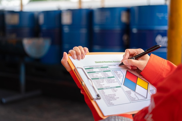 A worker is checking on the hazardous chemical material information form with background of chemical