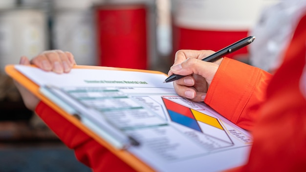 A worker is checking on the hazardous chemical material information form with background of chemical