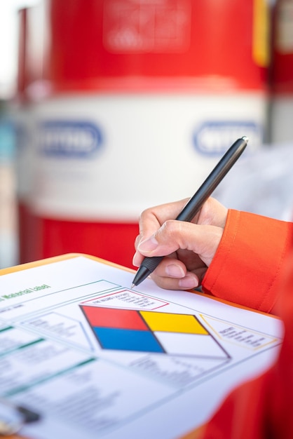 A worker is checking on the hazardous chemical material information form with background of chemical