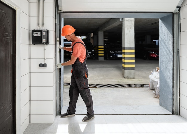 The worker is checking with the water level the vertical guide of the lift gate.