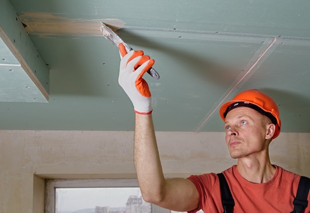 The worker is filling the plasterboards seams with gypsum putty