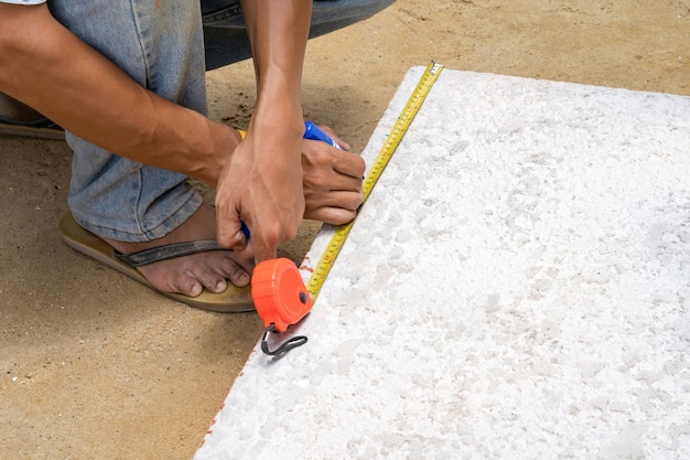 Worker is measure brick foam plate board before installation on construction site by tapeline