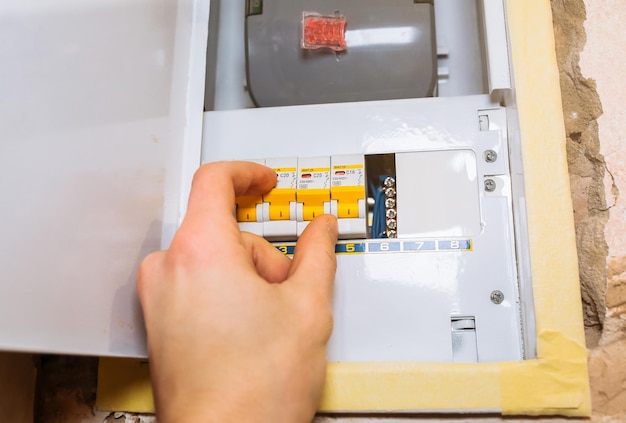 Worker is pressing switch on electrical panel Maintenance repair works renovation in the flat Restoration indoors