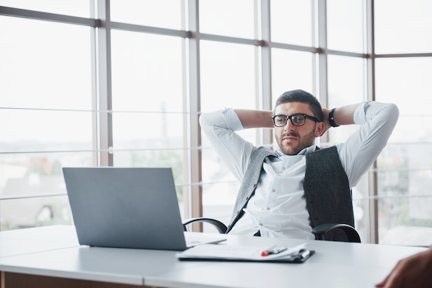 Worker is a young man with a laptop in the office.