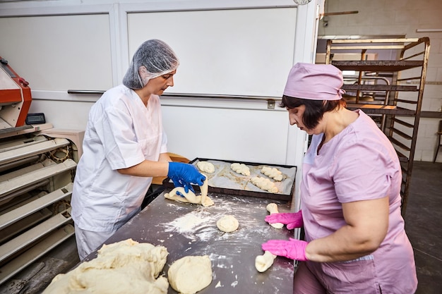 Worker in a large bakery industrial production of bakery products on an assembly line Teamwork woman at workplace