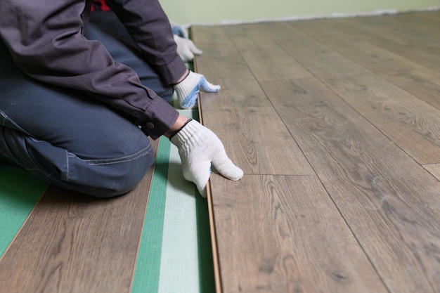 Worker lays the laminate in the apartment laminate is lying on the floor in the apartment the master...