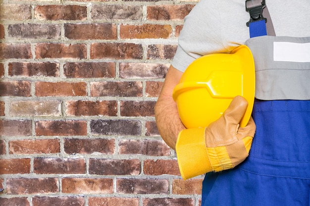 Worker man with helmet on brick wall background