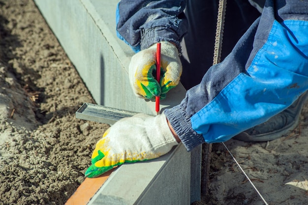 A worker measures a concrete block with a ruler closeup