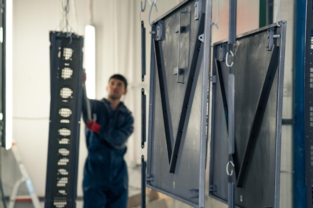 Worker moves metal parts to a powder coating booth