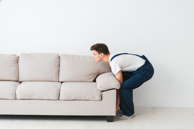 Worker in overalls lifts up sofa