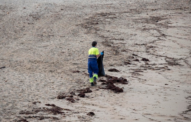 Worker picking up trash from the beach sand