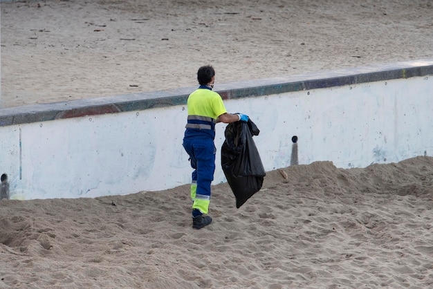 Worker picking up trash from the beach sand