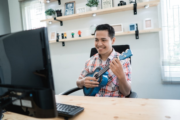 Worker playing with his guitar while looking at his computer