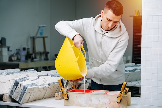 Worker pouring gypsum plaster in open form for mold casting for making tableware on a table from soft plastic basket