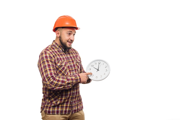 Worker in protective helmet holding alarm clock on white. Time to work. Building construction time