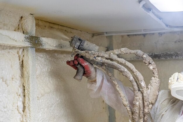 Worker in a protective suit insulates the walls with polyurethane foam