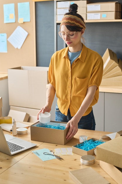 Worker putting packed products in cardboard boxes before export or shipping