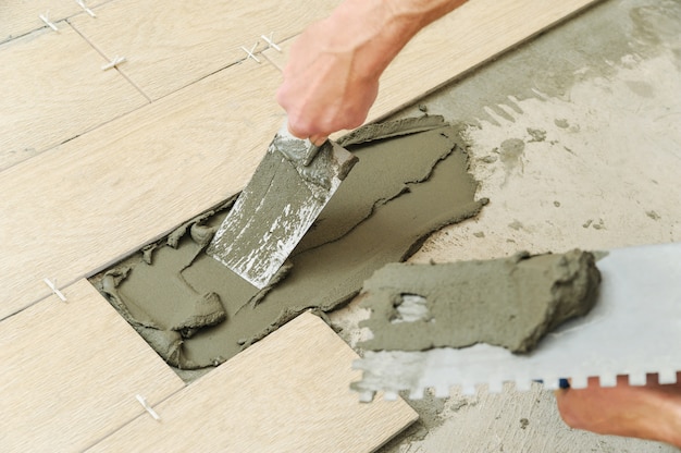 Worker putting tiles on the floor.