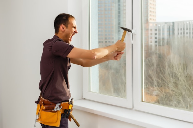 worker repairs windows with a hammer