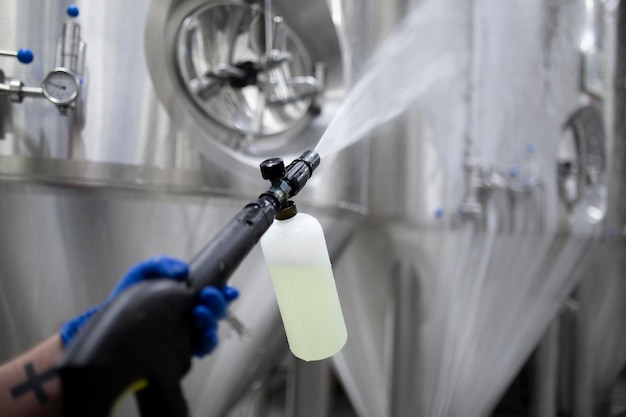 Photo a worker's hand hold a high pressure cleaner gun and put foam on equipment on the factory