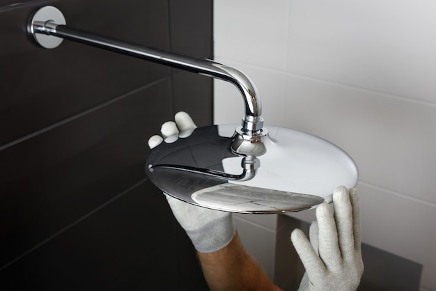 The worker's hands install the head of the built-in shower faucet