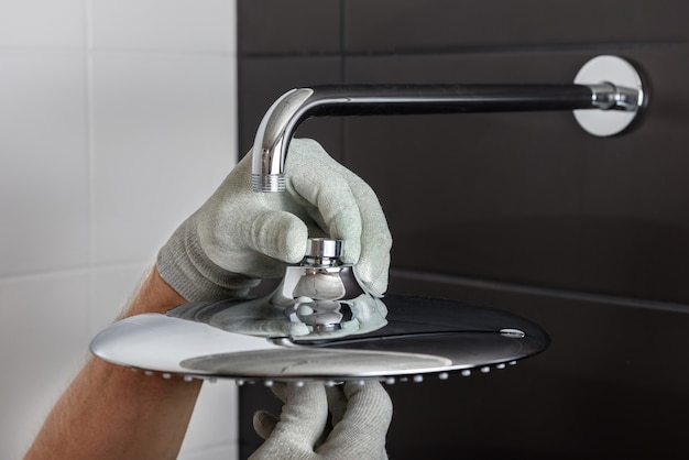 The worker's hands install the head of the built-in shower faucet.